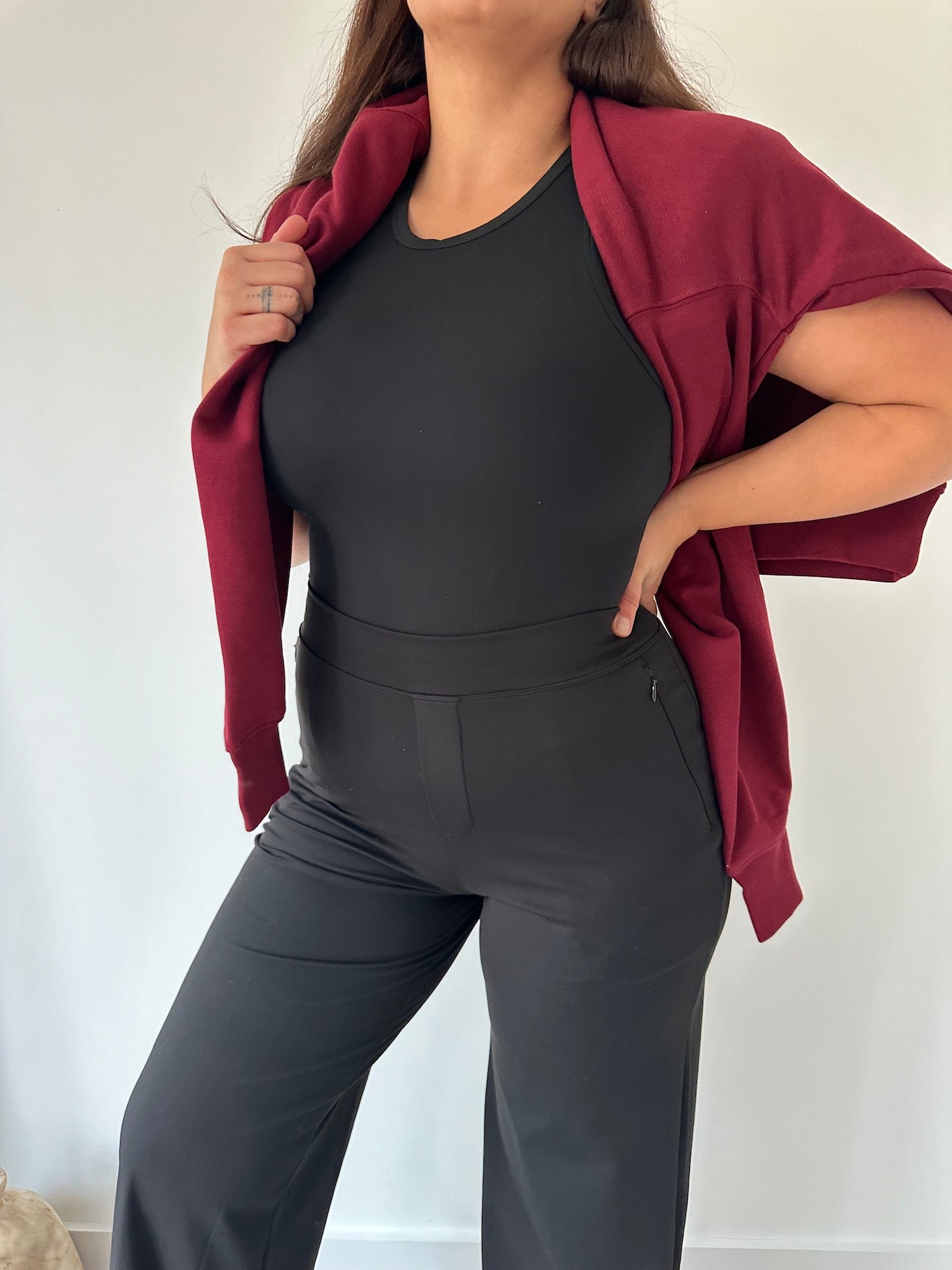 Curvy woman in black Ninepine Asana Relaxed Trousers, styled with a soft top and burgundy sweater, highlighting comfortable stretch trousers for everyday wear