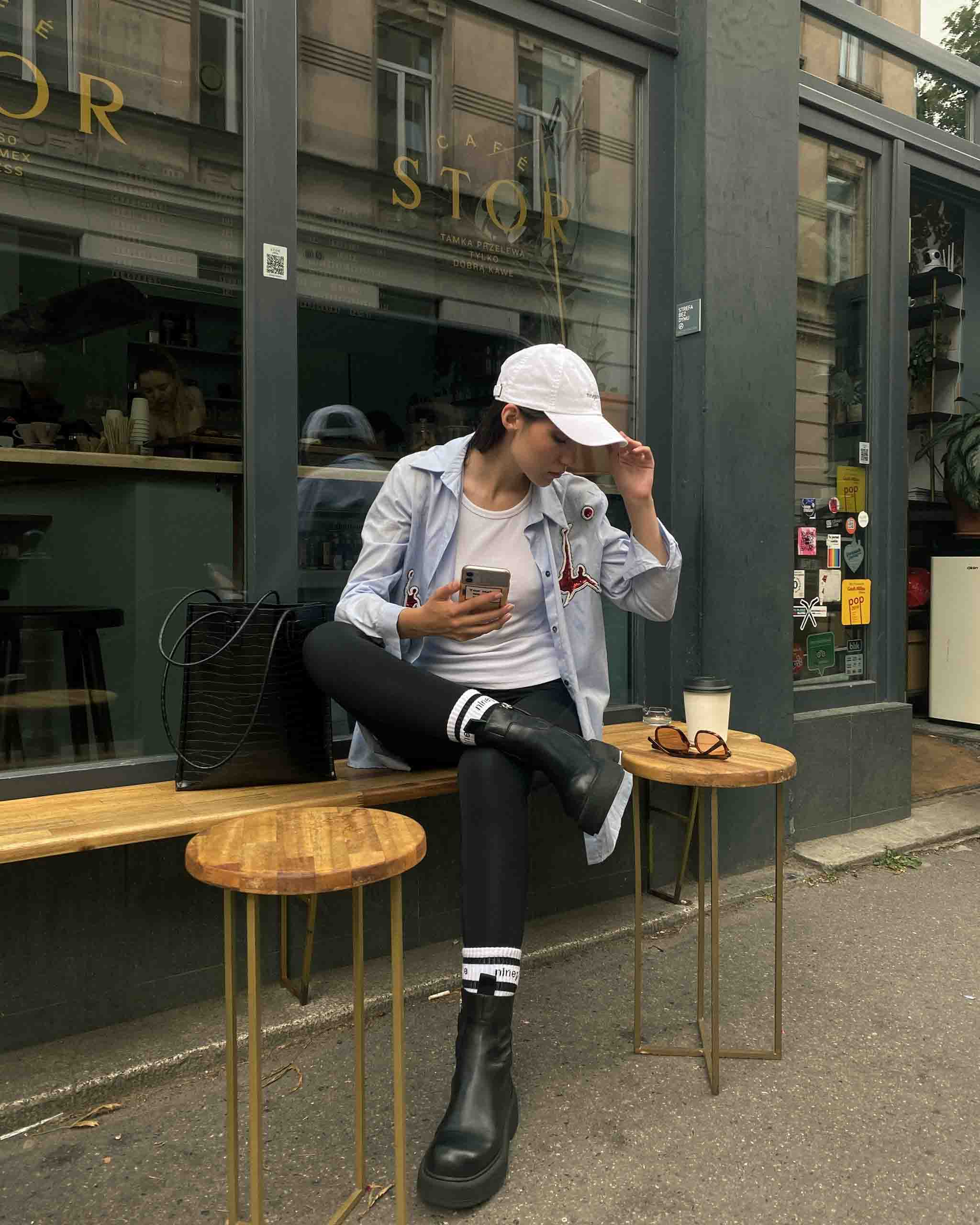Girl in ninepine cap sitting outside a hip cafe