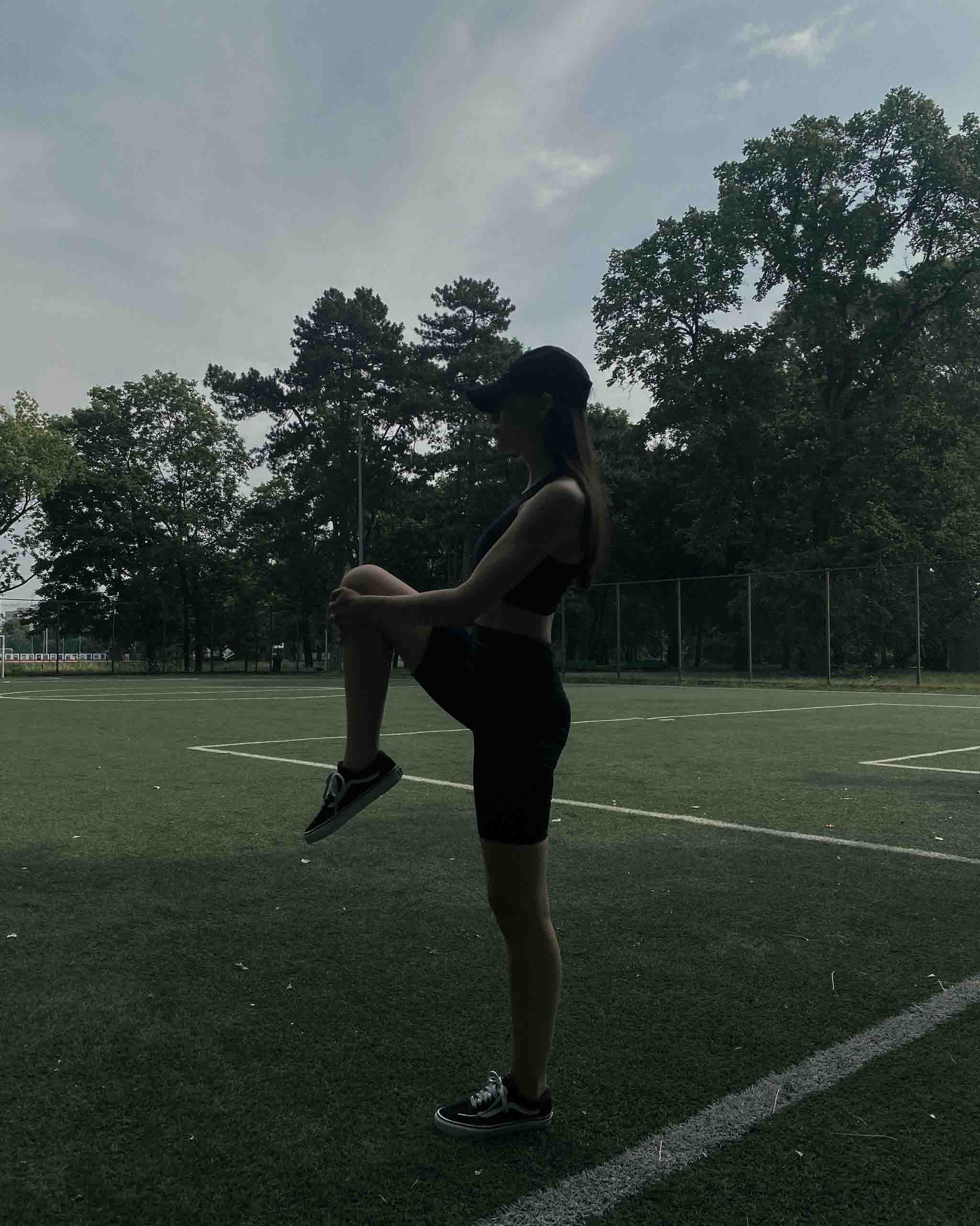 Girl on synthetic football field stretching in ninepine activewear set